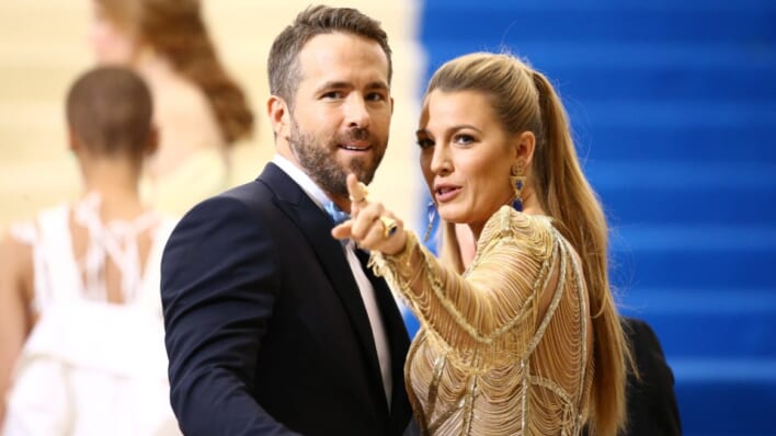 Blake Lively pointing off camera with husband Ryan Reynolds.