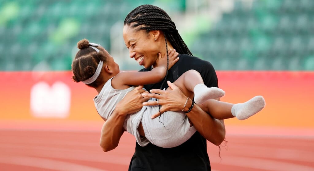 Allyson Felix holding daughter and smiling. 