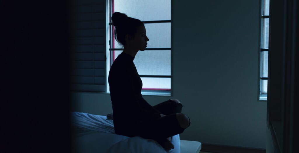 woman sits up awake in bedroom