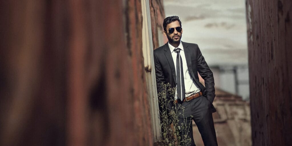 Man in suit and sunglasses leaning on wall by Kazi Mizan on Unsplash