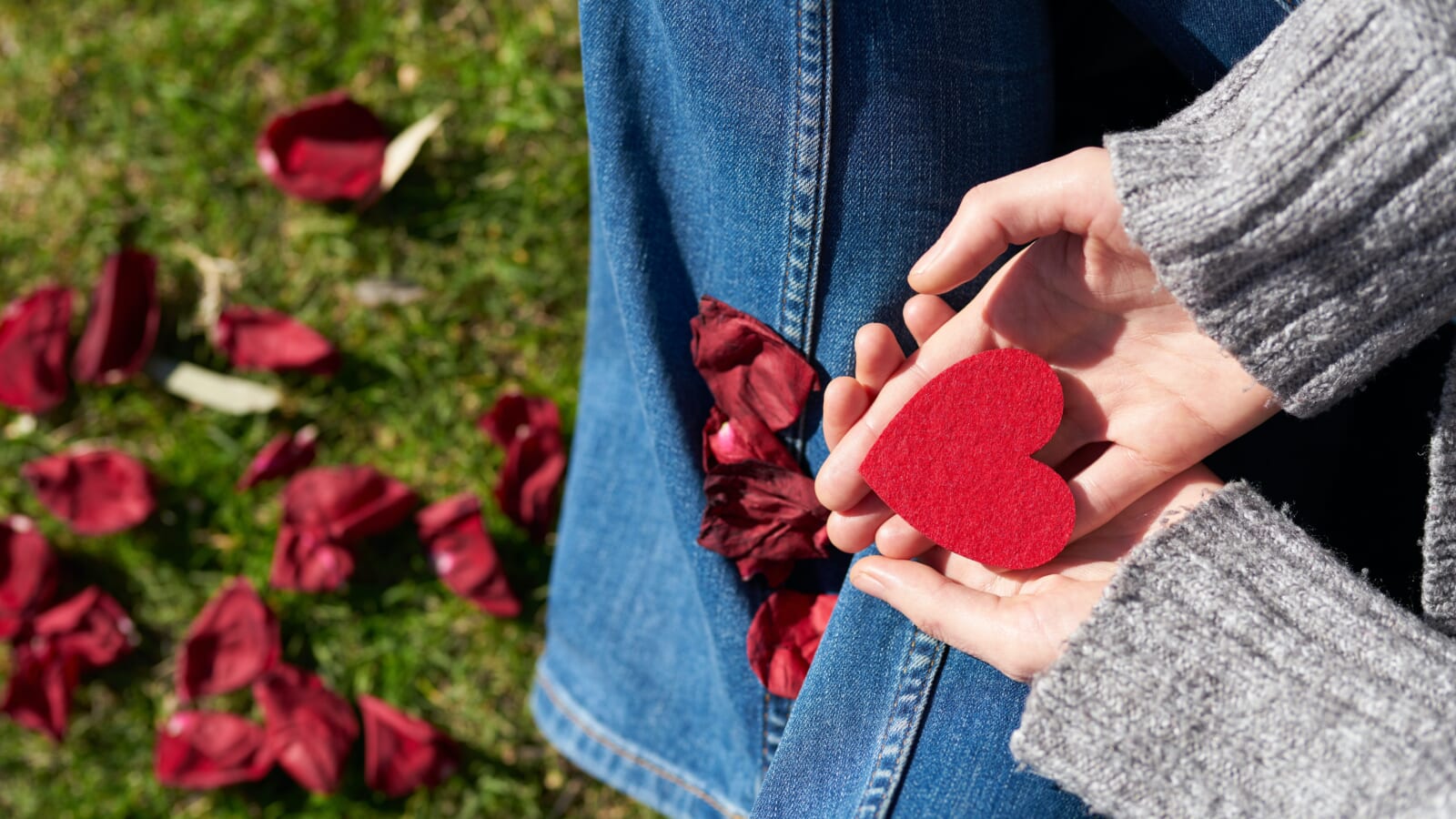 person holding a red paper heart in her hands